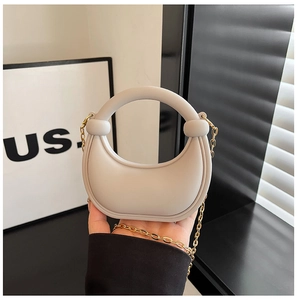 Detail of a mini beige semi-circle bag with gold chain and matte silicone texture