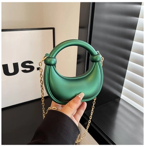 Detailed close-up of emerald green crescent handbag with matte texture and gold chain strap