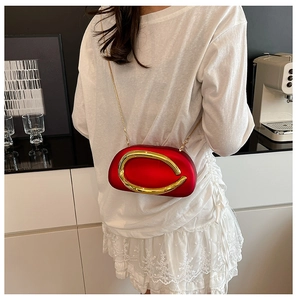 Red acrylic oval clutch with gold C-logo buckle and chain strap on shoulder