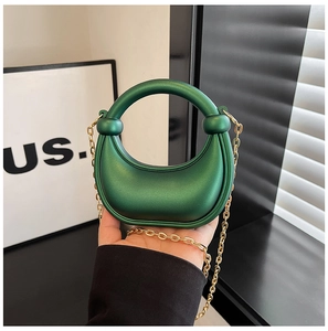 Detail of forest green crescent bag with metallic finish and gold circular handle