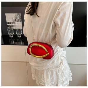 Detailed view of a red mini handbag with large gold metal ring and elegant chain strap