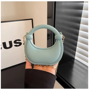 Detail of mint green mini silicone handbag with gold chain strap and ring handle