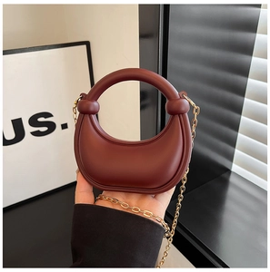 Detail of a mini burgundy crescent bag with matte finish and gold chain strap