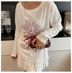 Model wearing white long sleeve cotton tee with red candle graphic and acrylic clutch bag