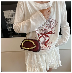 Detail of burgundy hard shell evening clutch with oversized gold oval metal buckle