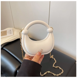 Close-up of white half-moon mini bag with knotted handle and golden chain strap