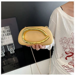 Detail of apricot clutch bag with gold C-shaped metal handle and crossbody chain strap
