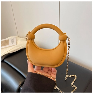 Detail of a ginger semi-circle handbag with matte texture and fine gold metal chain strap