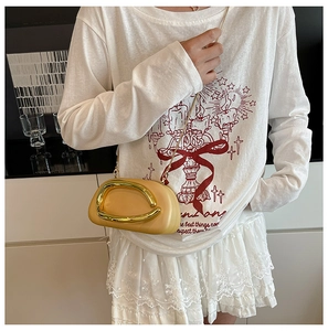 Detail of pale yellow evening bag with designer gold ring handle and metal chain strap