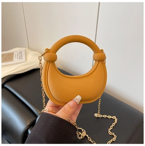 Detail of a ginger yellow mini half-moon bag with round handle and gold chain strap