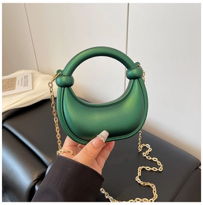 Detail of a dark green metallic crescent mini bag with a round handle and gold chain