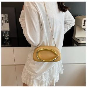 Detail of a khaki acrylic clutch with large gold C-hardware and chain strap worn on shoulder
