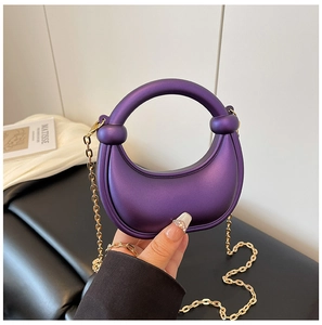 Detail of purple crescent handbag with matte texture, round handle, and gold metal chain