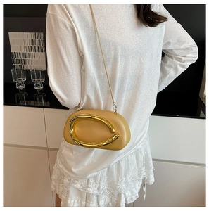 Detail of light yellow acrylic crossbody bag featuring a large gold C-clasp and chain strap