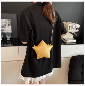 Star-shaped yellow crossbody bag with gold chain strap shown in a modern lifestyle setting
