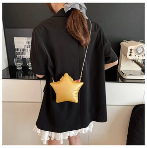 Golden star-shaped chain crossbody bag shown on a model in a minimalist setting