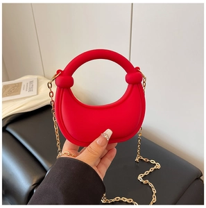 Detail of red half-moon mini handbag with golden chain strap and matte texture