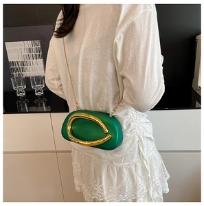 Green acrylic evening clutch with gold metal handle and chain strap on a white outfit