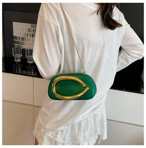 Detail of green acrylic clutch bag with large gold metal ring and elegant chain strap