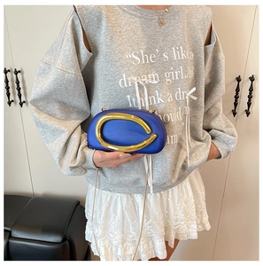 Detail of royal blue hard shell clutch with decorative gold metal ring and chain strap