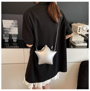 Chic silver star-shaped crossbody bag with slim metal chain shown in an urban cafe setting