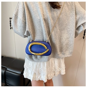 Close-up of royal blue acrylic clutch with gold metal handle and chain strap on model