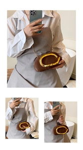Detail of a brown pleated evening bag with a large gold oval handle and chain strap