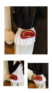 Detail view of the red crossbody bag showing metallic gold ring and chain strap styling