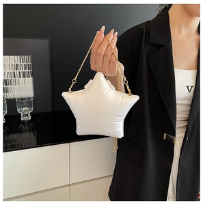 Detail of white star-shaped crossbody bag with gold metal chain strap on model