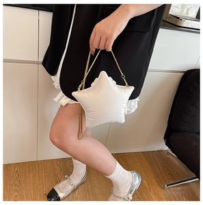 Detailed stitching and gold chain on a white star-shaped crossbody bag worn by model