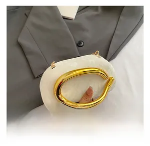 Close-up of a white marble texture clutch with a sleek gold metal ring handle