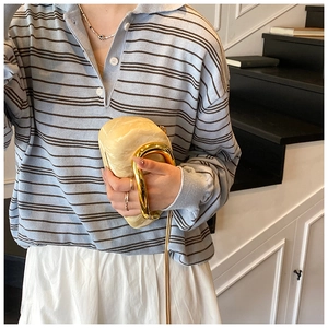 Chic cream marble hard shell clutch with a bold gold metal ring handle shown in detail