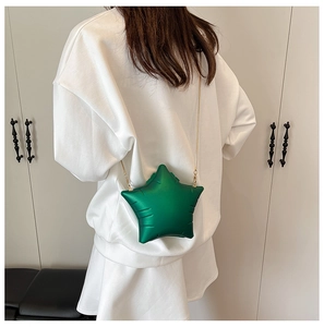 Detail of green star-shaped crossbody bag featuring metallic chain strap on model