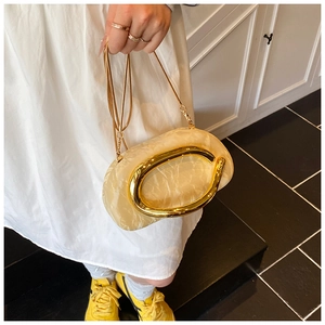 Detail view of acrylic clutch bag with marble pattern and large gold metal handle