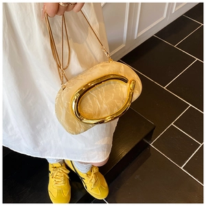Detail of marble texture clutch with oval gold metal handle and slim chain strap