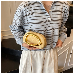 Detail of cream marble texture acrylic clutch bag with gold C-handle and chain strap