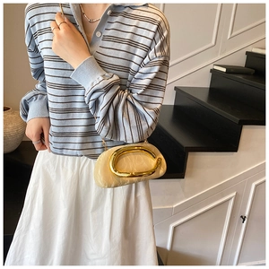 Detail of cream cloud bag featuring gold C-handle and delicate metal chain strap