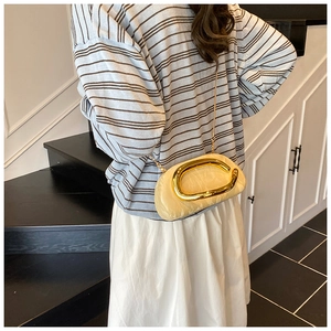 Detail of cream pleated cloud bag with gold metal oval handle and chain strap on model