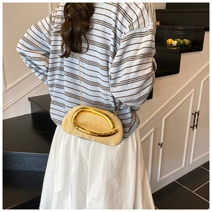 Model wearing a vintage beige marble acrylic clutch with gold chain and metal ring detail