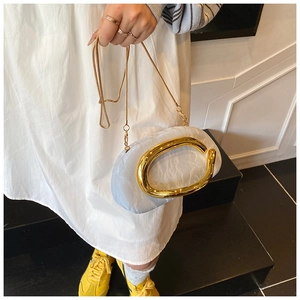 Detail of light blue pleated clutch featuring a large gold ring handle and snake chain