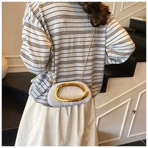 Detail of light blue mini chain bag with a large golden oval buckle and metal strap