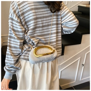 Detail of light blue pleated clutch bag with bold gold irregular metal handle and chain