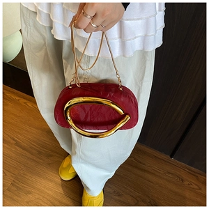 Detail of burgundy acrylic clutch featuring vintage gold oval handle and chain strap