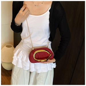Detail of burgundy suede oval bag with large gold C-clasp and elegant metal chain