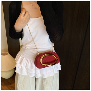 Detail view of burgundy oval chain bag featuring a large gold C-shaped metal buckle