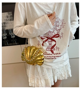 Detail of a golden shell evening clutch with pearl accents and a sleek chain strap