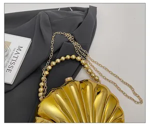 Detailed view of a gold shell-shaped evening clutch bag with chain strap and bead handle