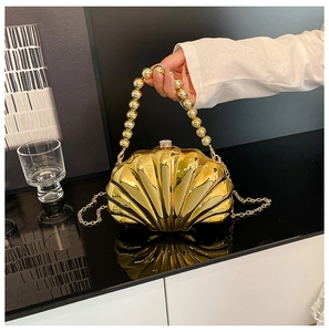 Close-up of golden shell evening bag with spherical handle and metallic chain strap
