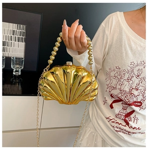 Close-up of golden shell-shaped mini bag with metallic texture and beaded chain handle