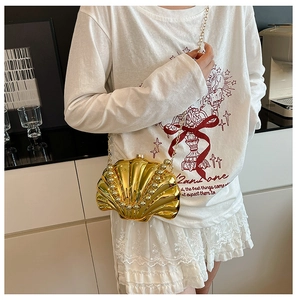 Detail of golden shell-shaped handbag with pearl embellishments and metal chain